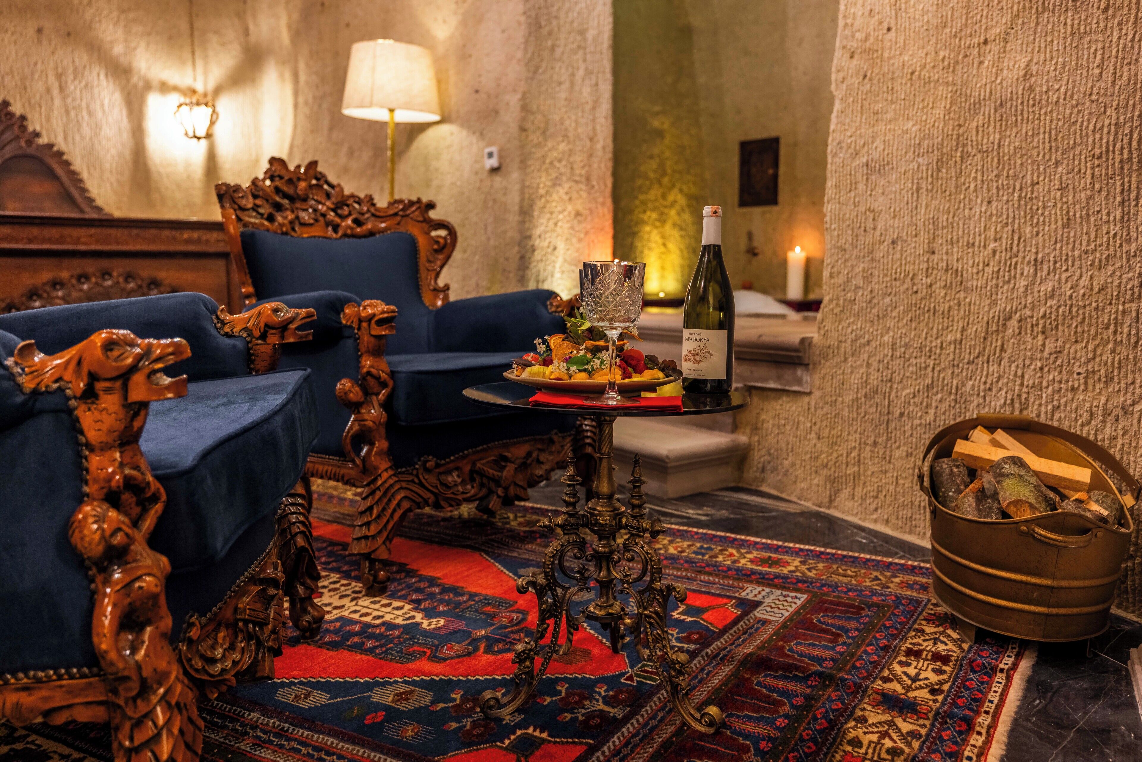 Una habitación con sofá azul, una mesa con una botella y vasos, alfombra estampada y pared con textura.