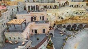 A courtyard with stone buildings, outdoor seating, and a staircase. - Signature Cave Cappadocia, Trademark Collection by Wyndham (Ürgüp)