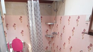 Un baño con inodoro rosa, ducha, lavamanos y bidé.
