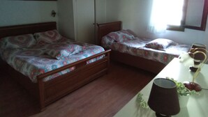 Un dormitorio con dos camas individuales, un armario, una mesita de noche con lámpara y una ventana con cortinas.