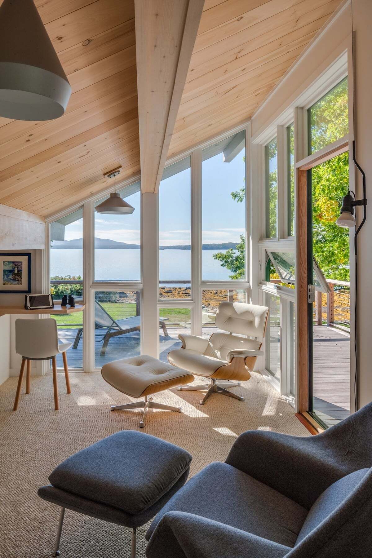 Un interior moderno con ventanas amplias, techo de madera y vistas al exterior.