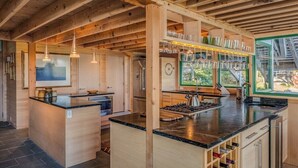 A modern kitchen with wooden beams, a central island, and a wine rack. - Oak Point Bluff! Oceanfront! (Trenton)