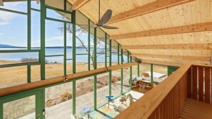 A wooden cabin with a balcony overlooking a lake, a ceiling fan, and a view of the landscape. - Oak Point Bluff! Oceanfront! (Trenton)