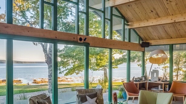 A spacious living area with large windows, a wooden ceiling, and a view of the water. - Oak Point Bluff! Oceanfront! (Trenton)