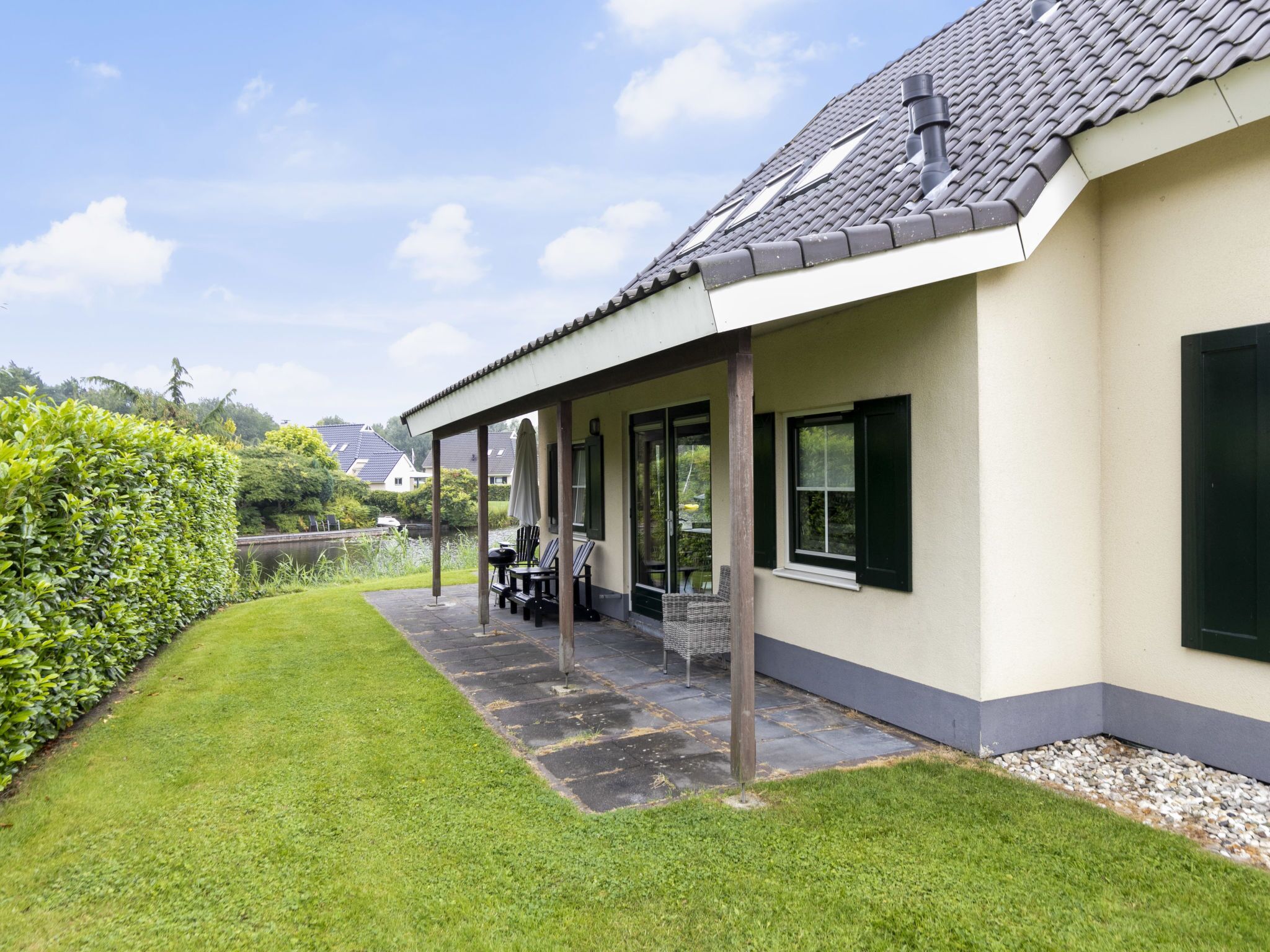 A house with a covered patio, a lawn, and a view of the neighborhood.