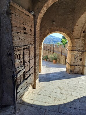 Un corredor de piedra en arco con vistas a un paisaje montañoso a través de un arco abierto.