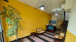 Ein Empfangsbereich mit einer Rezeption, gestreiften Stühlen, einer Zimmerpflanze und einer Treppe.