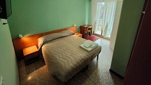 Ein Hotelzimmer mit Bett, Schreibtisch und einem fensterbepflanzten Fenster.