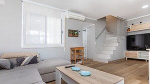 A modern living room with a sofa, a coffee table, and a staircase leading to a kitchen area. - Vacation home Yoli by Interhome (Miami Platja)