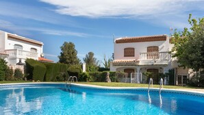 A swimming pool with clear blue water, surrounded by white buildings with red-tiled roofs and balconies. - Vacation home Yoli by Interhome (Miami Platja)