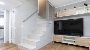 A modern living room with a staircase, a flat-screen TV, and built-in shelving. - Vacation home Yoli by Interhome (Miami Platja)