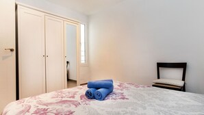 Un dormitorio con cama, una silla y un armario.