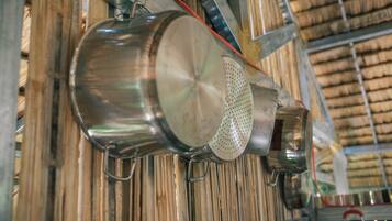 A stainless steel kettle and colander hanging on a rack in a kitchen with wooden slats in the background.