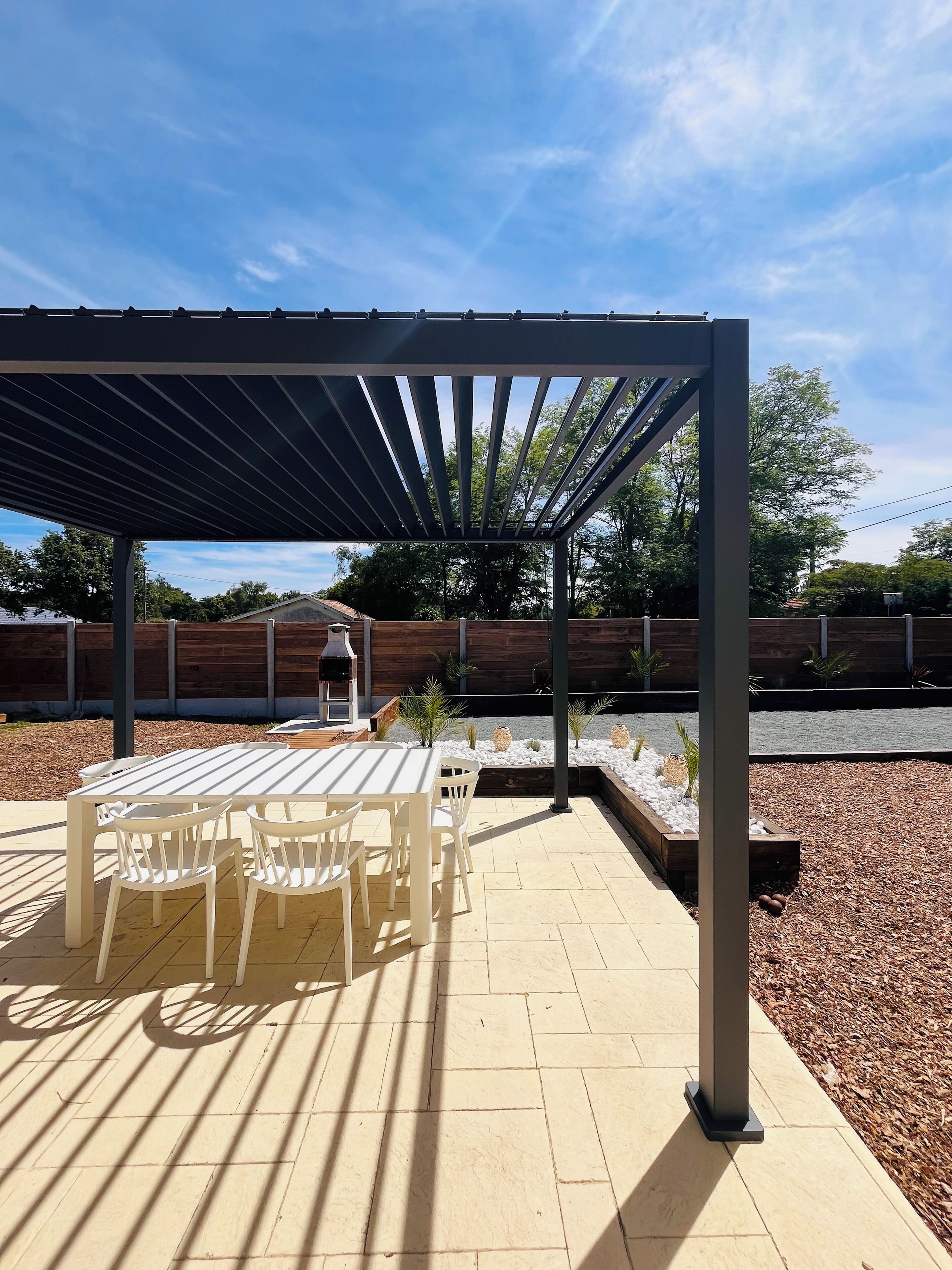 A covered patio area with a table and chairs, a barbecue grill, and a decorative planter.