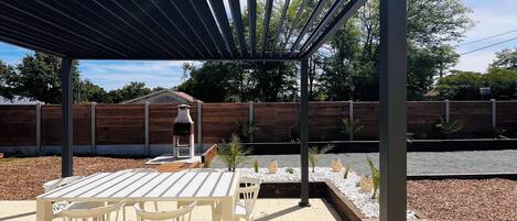 A covered patio area with a table and chairs, a barbecue grill, and a decorative planter.