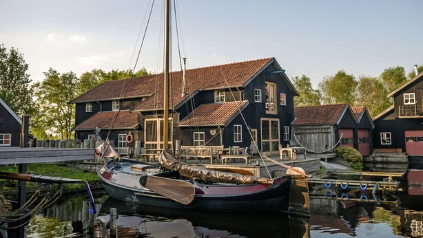 A traditional wooden house with a red-tiled roof, docked boats, and a calm water body. - Bungalowpark It Wiid by Interhome (Eernewoude)