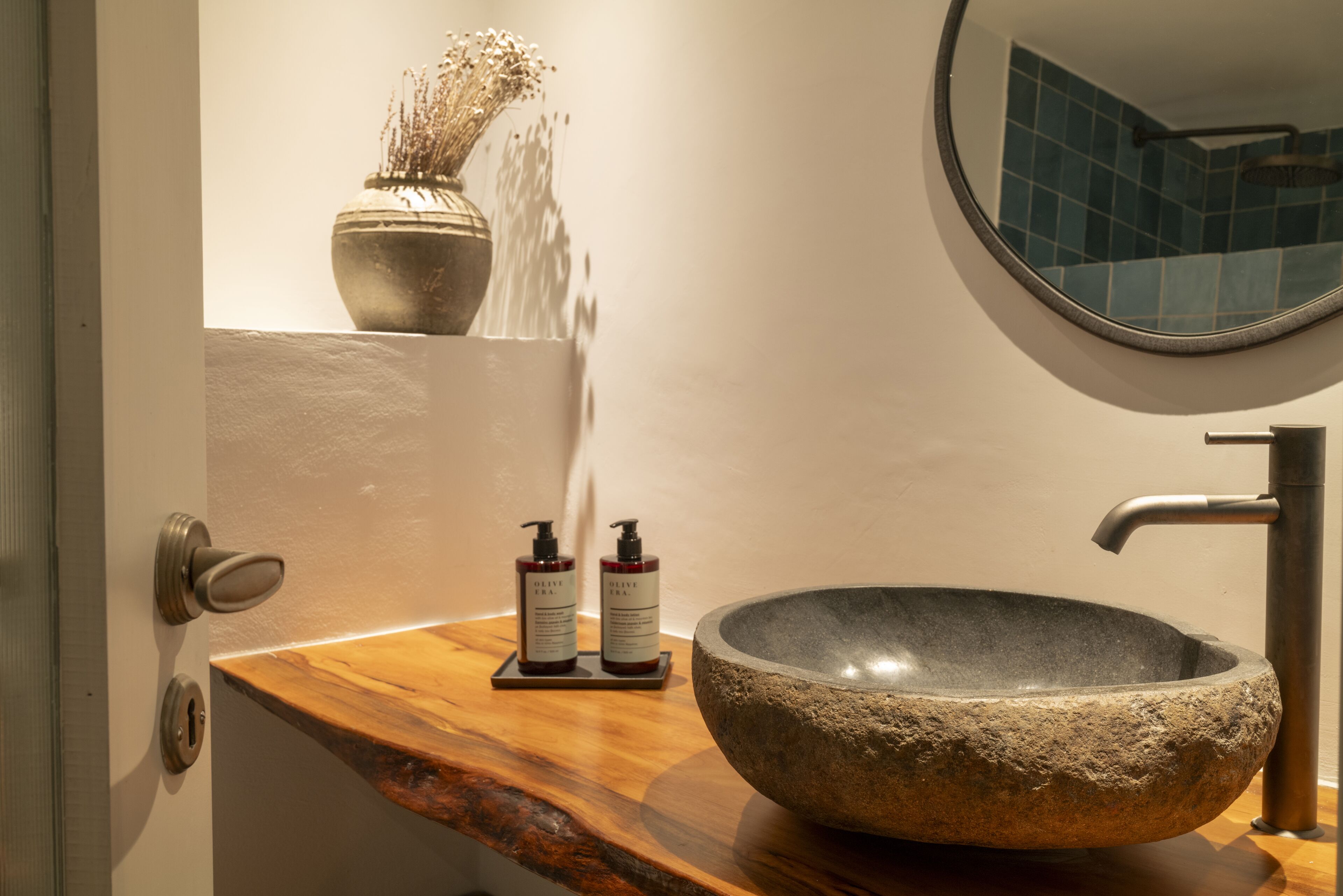 Un baño con lavamanos de piedra, encimera de madera y espejo.