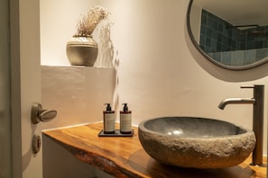 Un baño con lavamanos de piedra, encimera de madera y espejo.