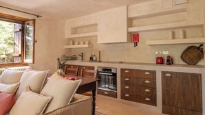 A modern kitchen with wooden cabinets, a built-in oven, and a dining area with a table and chairs. - Casa Oliva (Treis Elies)