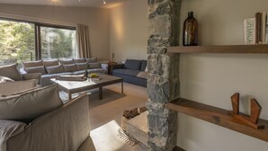 A modern living room with a stone fireplace, a sofa set, and a coffee table. - Casa Oliva (Treis Elies)