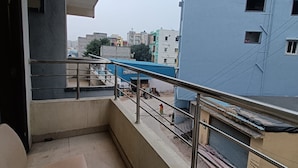 A balcony with a chair, a metal railing, and a view of neighboring buildings. - Way Inn Familiar (Hyderabad)