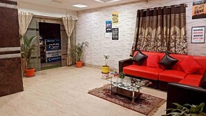 A modern living room with a red sofa, a glass coffee table, and potted plants. - Way Inn Familiar (Hyderabad)
