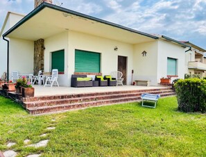 A modern house with a covered patio, outdoor seating, and a well-maintained lawn. - Beachfront villa located directly on the promenade in Castiglione della Pescaia (Castiglione della Pescaia)
