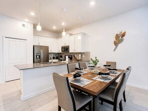 A modern kitchen with white cabinetry, a central island, and pendant lighting.