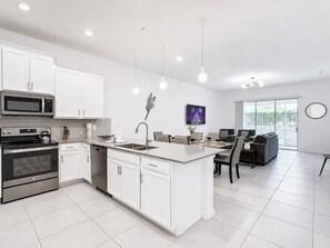 Une cuisine moderne avec des meubles blancs, des appareils en acier inoxydable et un îlot central.