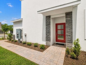 A modern building with a red door, stone accents, and a paved walkway.