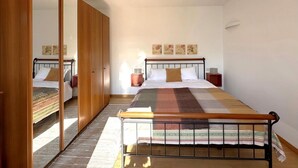 Ein Schlafzimmer mit einem Bett, einem Holzschrank, Nachttischen und Bildern an der Wand.