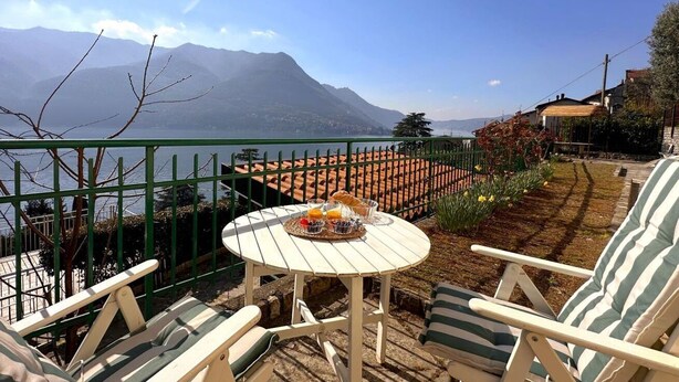 Eine Terrasse mit gedecktem Tisch für das Frühstück, mit Blick auf einen See und Berge.