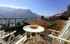 A terrace with a table set for breakfast, overlooking a lake and mountains. - Cà Alda – Lake Como View (Carate Urio)