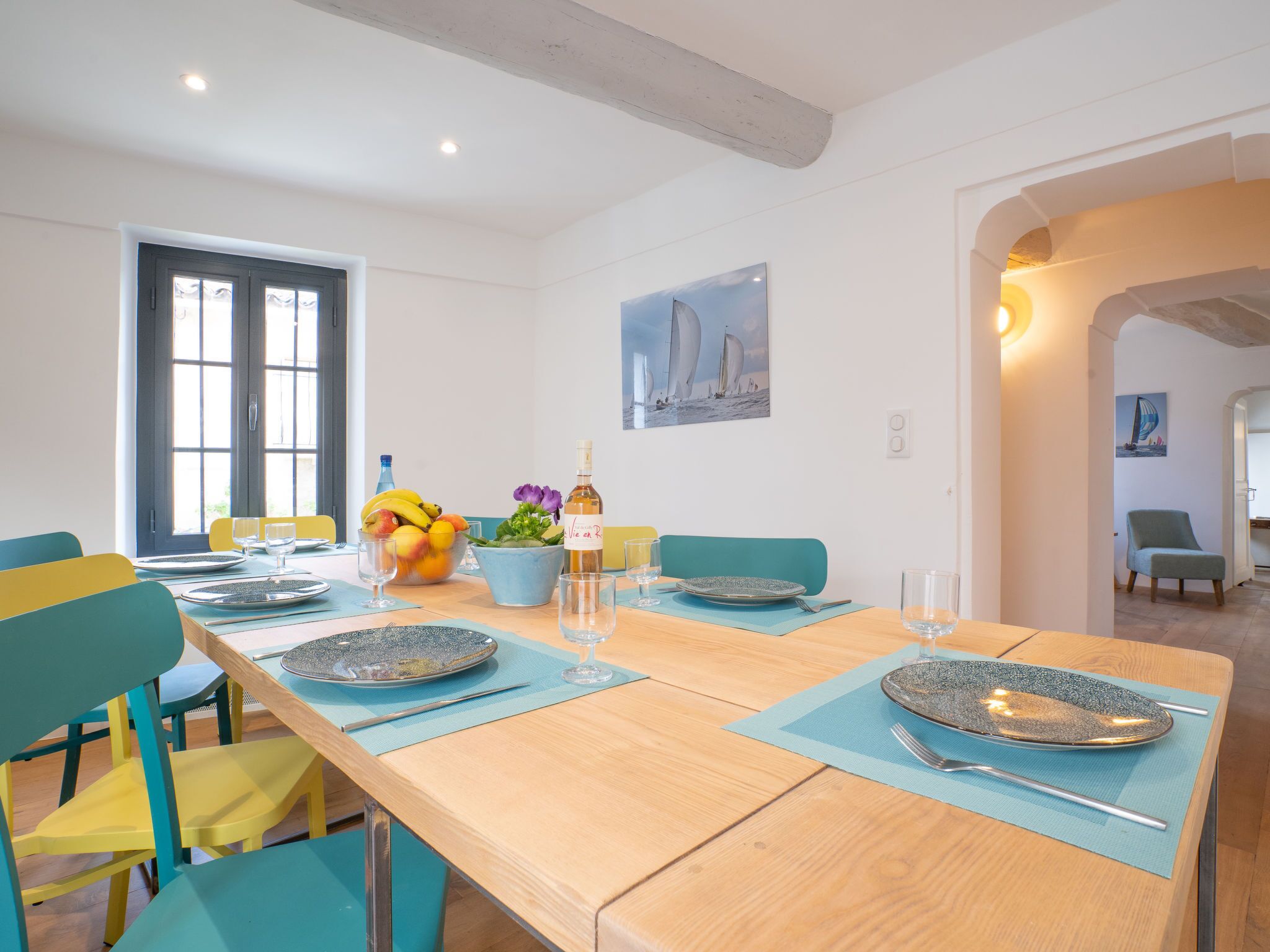 Een eethoek met een houten tafel voor vier personen, stoelen en een schaal met fruit.