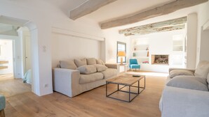 Un salon spacieux avec un plancher en bois, un canapé beige, un fauteuil bleu et une table basse.