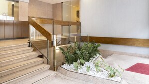 A modern interior with a staircase, glass railings, and a small indoor garden.