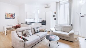 A modern living room with a sofa, a coffee table, and a dining area with a table and chairs.