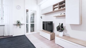 Un salon moderne avec un téléviseur, des étagères intégrées et une plante en pot.