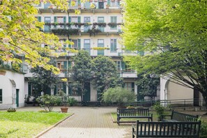 A courtyard with a paved walkway, benches, and lush greenery. - Easylife - Cosy apartment in Moscova/Sarpi (Milano)
