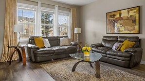 Un salon avec deux canapés en cuir, une table basse en verre et un tapis beige.