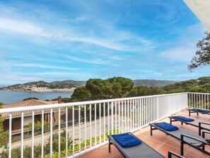Une terrasse avec des places assises extérieures et une vue panoramique sur une ville côtière et les collines environnantes.
