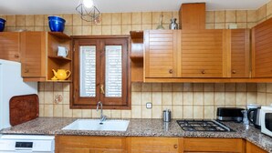 A kitchen with wooden cabinets, a granite countertop, a sink, a stove, and a microwave.