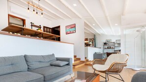Una sala de estar moderna con un sofá gris, una mesa de centro de vidrio y una silla de mimbre.