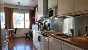 Et moderne køkken med rustfrie hvidevarer, en træbordplade og et spiseområde med et bord og stole.
