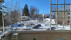 En balkon med udsigt over et snelandskab, et træbord med en potteplante og en blå stol.