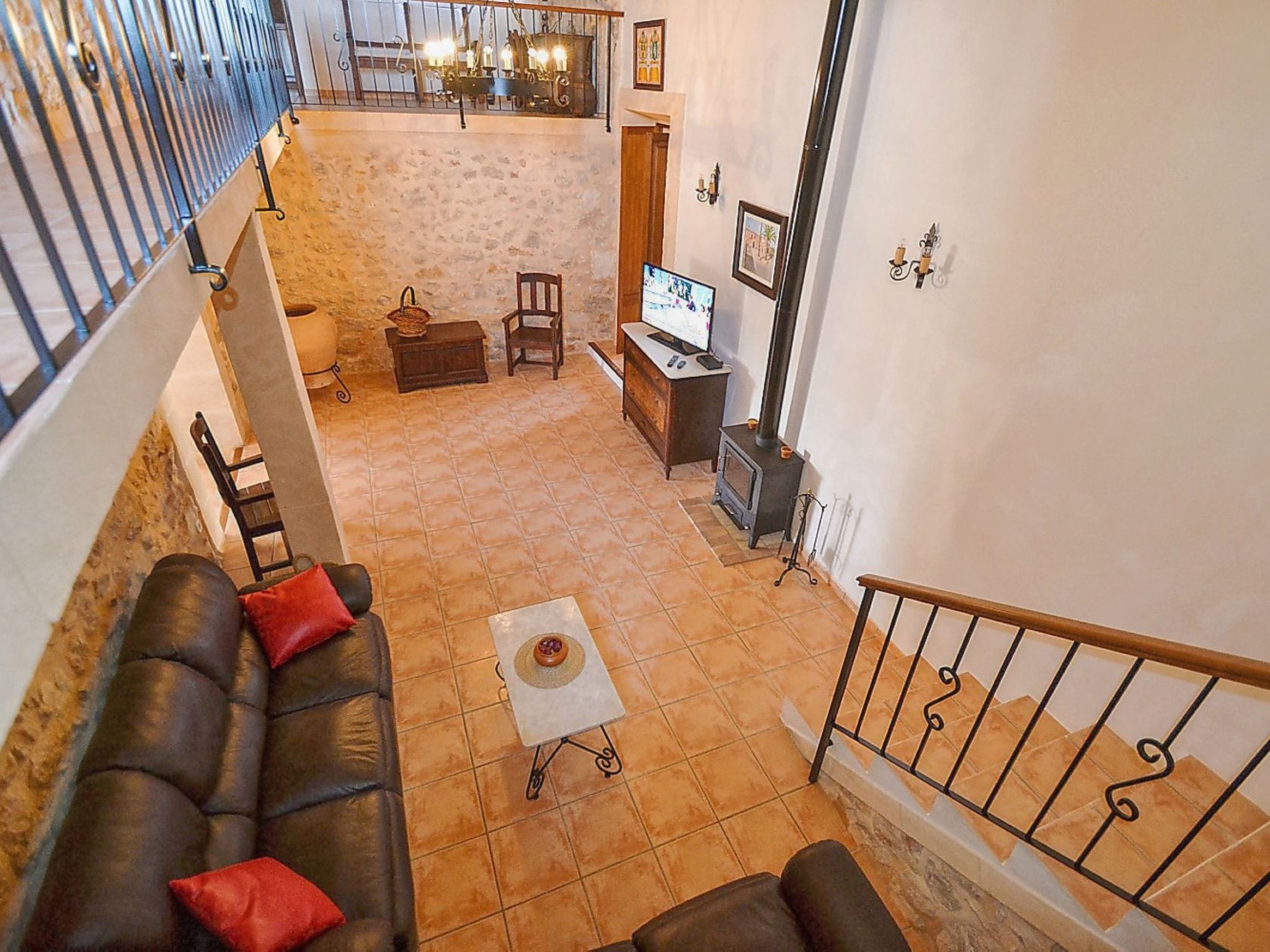 A spacious living area with a stone wall, a fireplace, a sofa, and a television.