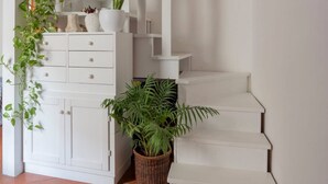 A staircase with white steps and a white wall. There is a white cabinet with drawers and a potted plant on the left. - Casa Livia Sperlongaresort (Sperlonga)