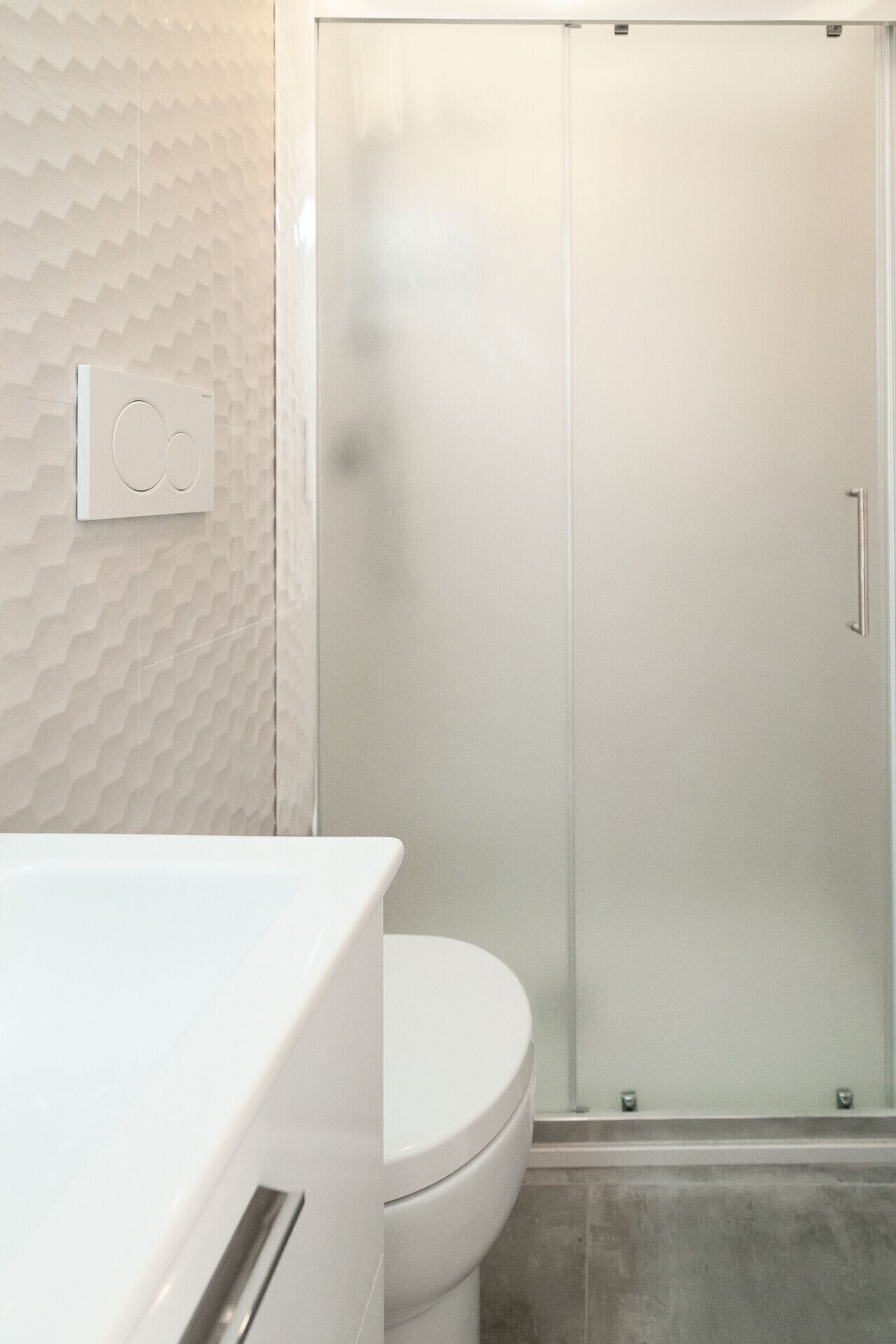 Un baño con inodoro, ducha con puerta de vidrio e interruptor de luz en la pared.
