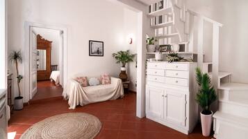 A spacious living area with a sofa, a large woven rug, and a white cabinet with shelves.