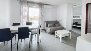 Una habitación moderna y bien iluminada con una mesa de comedor, sillas, un sofá y una pequeña mesa blanca.